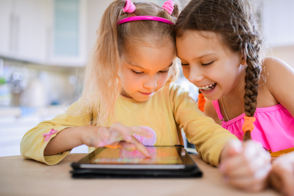 Two Little Sisters Play On A Tablet Pc